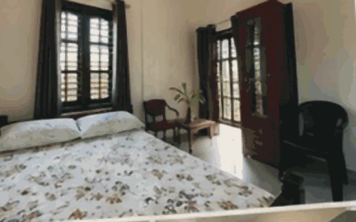 Room Two at Nadithaara, one double bed and a chair by the window